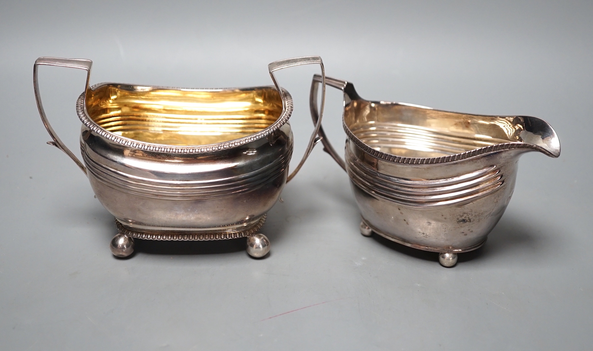 A George III silver cream jug, London, 1809 and a Georgian silver sugar bowl (marks rubbed), 11oz.